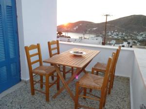 een houten tafel en 4 stoelen op een balkon bij Vasilis Place Ιos in Ios Chora