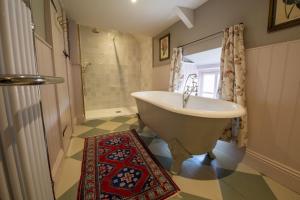 y baño con bañera, ducha y alfombra. en Beau Repaire, en Coneysthorpe