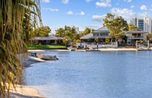 a boat on a body of water next to houses at Mooloolaba Waterfront Unit - sleeps 8 in Mooloolaba