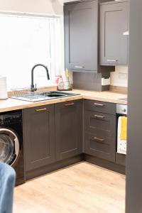 uma cozinha com armários cinzentos e um lavatório em Ideal Lodgings In Audenshaw em Manchester