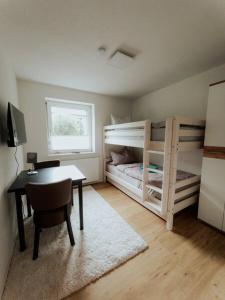 1 Schlafzimmer mit 2 Etagenbetten, einem Schreibtisch und einem Tisch in der Unterkunft Welcome Haus Allgäu in Memmingen