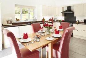 een keuken met een houten tafel en rode stoelen bij Wisteria Cottage Ceredigion in Ystrad Meurig