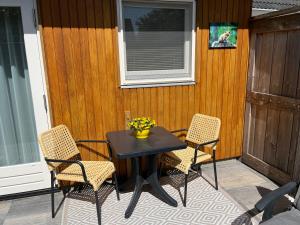 een tafel met stoelen en een vaas met bloemen op een patio bij Luxe kamer Chambre Renard met eigen terras in Zoutelande
