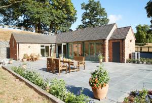 un patio con mesa y sillas y un edificio en Woodland Retreat en Burton upon Trent