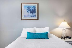 a bed with a blue pillow on top of it at Coconut Palms Beach Resort II in New Smyrna Beach