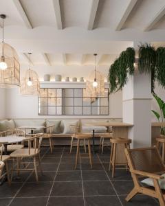 un restaurante con mesas y sillas de madera y macetas en Calendula Hotel, en Sant Feliu de Guíxols