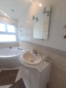 La salle de bains blanche est pourvue d'un lavabo et d'une baignoire. dans l'établissement Maison à Poitiers - Futuroscope, à Poitiers