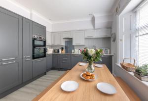 a kitchen with a wooden table and a vase of flowers at Landward Cottage Isle of Wight in Niton