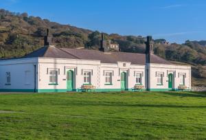 a large white building with green doors on a field at Landward Cottage Isle of Wight in Niton