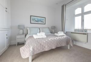 a white bedroom with a bed with two towels on it at Landward Cottage Isle of Wight in Niton