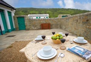 a table with glasses of wine and a bowl of fruit at Landward Cottage Isle of Wight in Niton