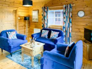 a living room with blue couches and a coffee table at Chalet 1 in Torcastle