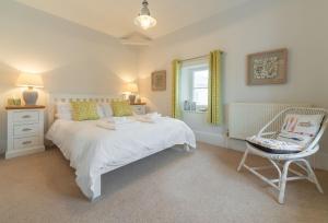 a bedroom with a white bed and a chair at Lodesman Cottage in Kingsgate