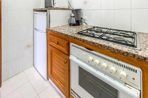a kitchen with a stove top oven next to a refrigerator at Polcent 3 Pequeño apartamento cercano a la playa in S'Agaro