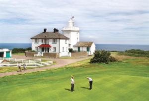 two people playing golf in front of a lighthouse at The Link in Cromer