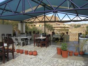 a patio with tables and chairs and a blue umbrella at Hotel Golden City with Swimming Pool in Jaisalmer