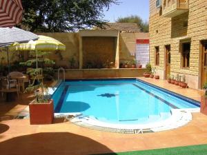 una gran piscina azul con sombrilla en Hotel Golden City with Swimming Pool, en Jaisalmer