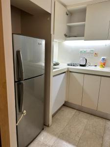 a kitchen with a refrigerator and white cabinets at MyHabitat - KLCC 2 bedroom in Kuala Lumpur