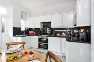 a kitchen with white cabinets and a wooden table at Solebay Cottage in Lower Boscaswell