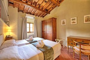 a bedroom with two beds and a wooden cabinet and a desk at Villa Bellostare by PosarelliVillas in Cantagrillo