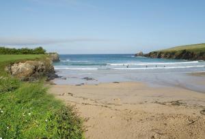 a beach with people surfing in the ocean at Verity Cottage in Saint Merryn