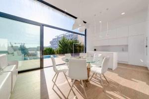 a dining room with a glass table and white chairs at Preciosa villa con la piscina en las Colinas in Orihuela