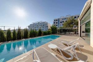 a swimming pool with lounge chairs next to a building at Preciosa villa con la piscina en las Colinas in Orihuela
