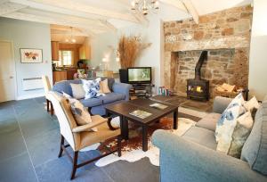 a living room with a couch and a table and a fireplace at Spring Water Barn in Helston