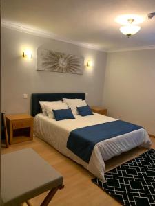 Schlafzimmer mit einem großen Bett mit blauer und weißer Bettwäsche in der Unterkunft AL Restaurante A Lampreia in Santa Comba Dão