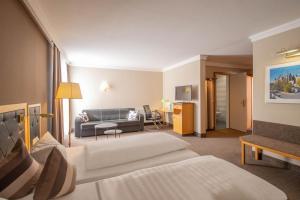 um quarto de hotel com uma cama e um sofá em Hotel Tanne Ilmenau em Ilmenau