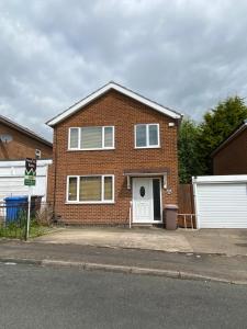 a red brick house with a white garage at Birch Avenue House, entire house with 4 bedrooms, free parking, free WI-FI, Smart TV, washing machine, easy access to M1 in Ilkeston