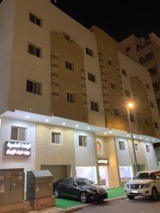 two cars parked in front of a building at night at فندق الواحة الماسية نجمة 1 in Makkah