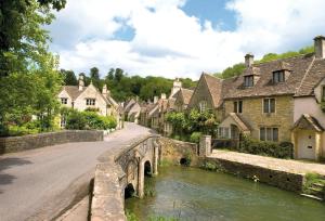 an old stone bridge over a river in a village at The Gates in Castle Combe