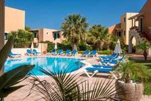 una piscina con tumbonas y sombrillas azules en Dia Apartments, en Hersonissos