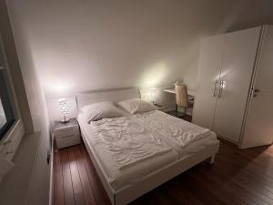 a bedroom with a white bed and a table and chair at Ferienhaus Sarcander in Glowe