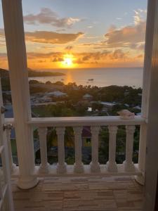 einen Blick auf den Sonnenuntergang vom Balkon eines Hauses in der Unterkunft Atlantic Breeze Apartments, Canouan Island in Canouan