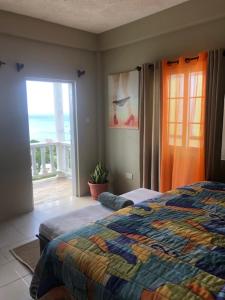 a bedroom with a bed and a view of the ocean at Atlantic Breeze Apartments, Canouan Island in Canouan