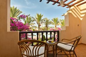 a balcony with a table and chairs and palm trees at Dream Lagoon Resort & Aqua Park in Marsa Alam City