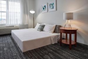 a hotel room with a bed and a table with a lamp at TownePlace Suites Medford in Medford