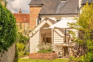 een wit huisje met een tafel en een paraplu bij Densford Cottage in Amberley