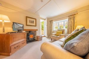 Densford Cottage في أَمبيرلي: غرفة معيشة مع أريكة وتلفزيون ومدفأة
