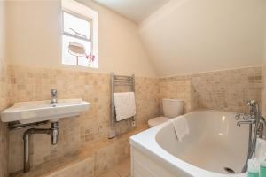 een badkamer met een bad, een wastafel en een toilet bij Densford Cottage in Amberley +25 foto's