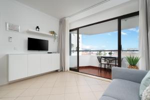een woonkamer met een bank en een televisie bij Sunny Studio W/ Balcony in Portimão by LovelyStay in Portimão