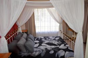 a bedroom with a canopy bed and a window at Holiday Flat Stormvoel 547 in Hazyview