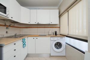 een keuken met witte kasten en een wasmachine bij Sunny Studio W/ Balcony in Portimão by LovelyStay in Portimão