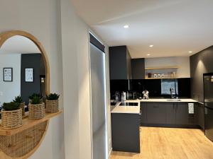 a kitchen with black and white cabinets and a mirror at Gem in Papanui Christchurch in Christchurch
