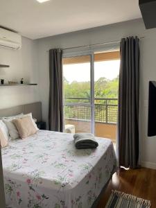 ein Schlafzimmer mit einem Bett und einem großen Fenster in der Unterkunft Flat Studio Granja Viana Completo 411 in Cotia