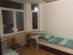 a bedroom with two beds and two chairs and windows at K&K Unterkunft GbR, Wohunung 3 in Duisburg
