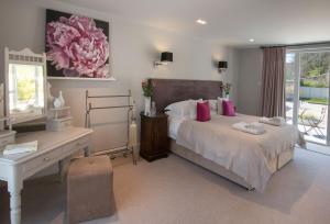 a bedroom with a bed with pink pillows and a desk at Brooks Lodge Sussex in Tarring Neville