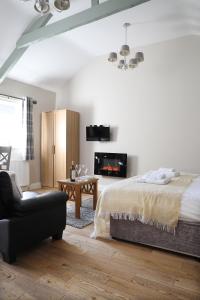 a bedroom with a bed and a couch and a chair at Avocet Cottage in Lucker